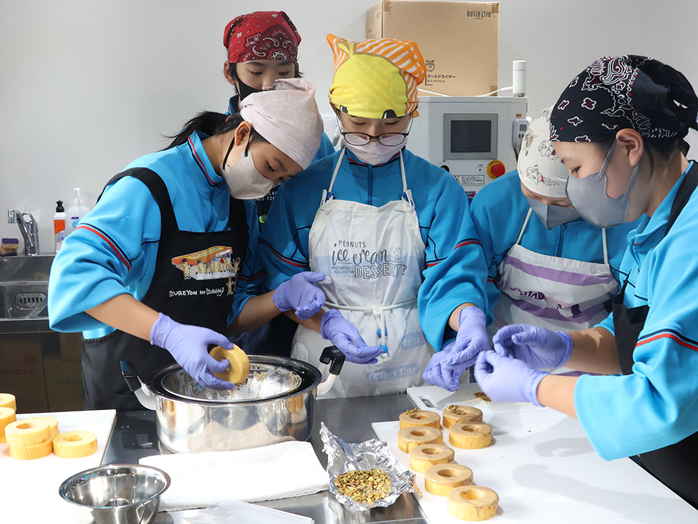 バウムクーヘンにチョコをつける作業をする生徒