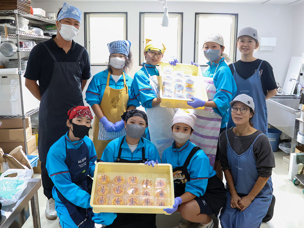 生徒とスタッフらで完成したバウムクーヘンを持ち集合写真