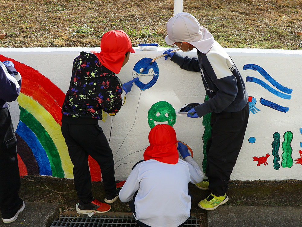 壁画に色塗りをする3年生の児童ら