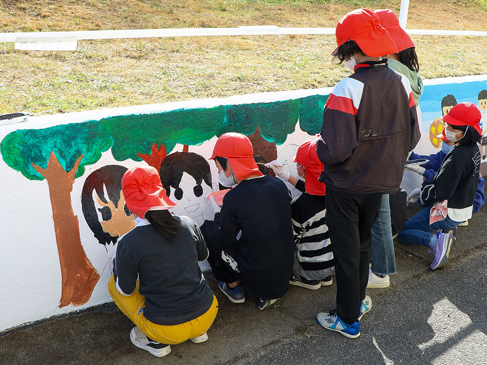壁画に色塗りをする5年生の児童ら
