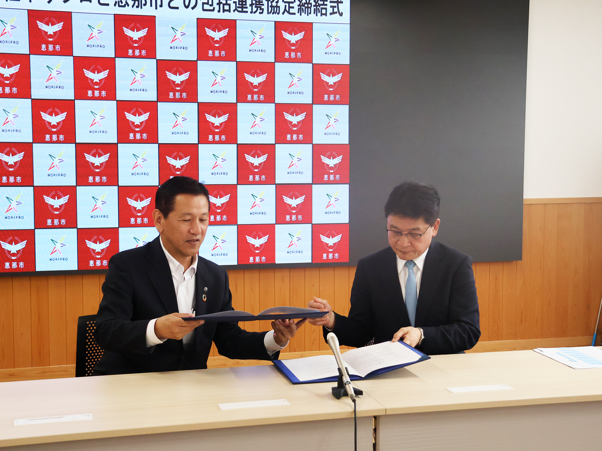 協定書を確認する小坂市長(左)と鈴木基之取締役(右)