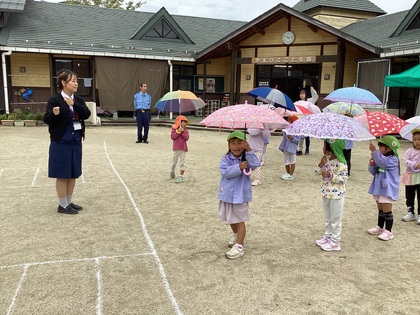 傘をさして園庭で横断練習