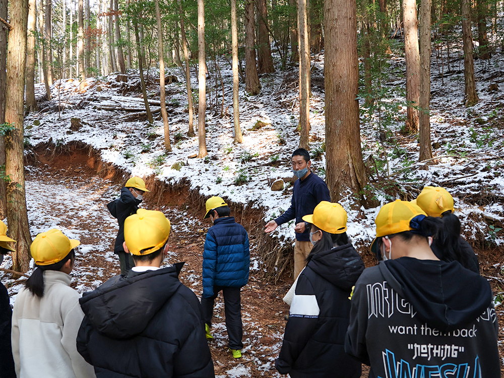長江さんが作った道と山を見学する児童ら