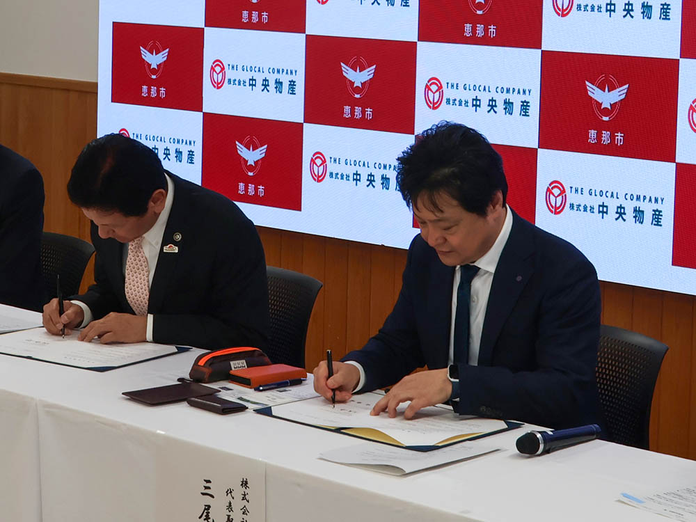 協定書に署名する三尾社長と小坂市長