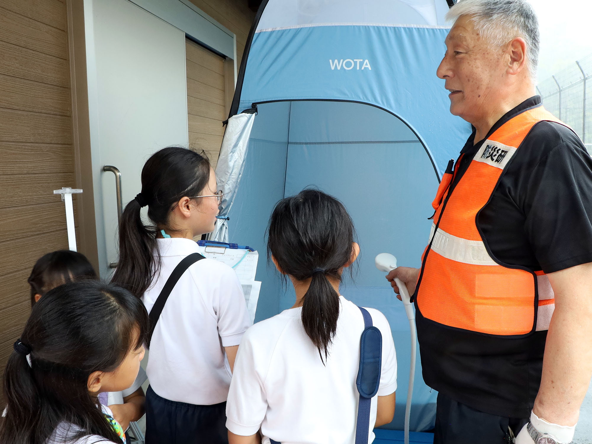 水循環式シャワーを見学する児童ら