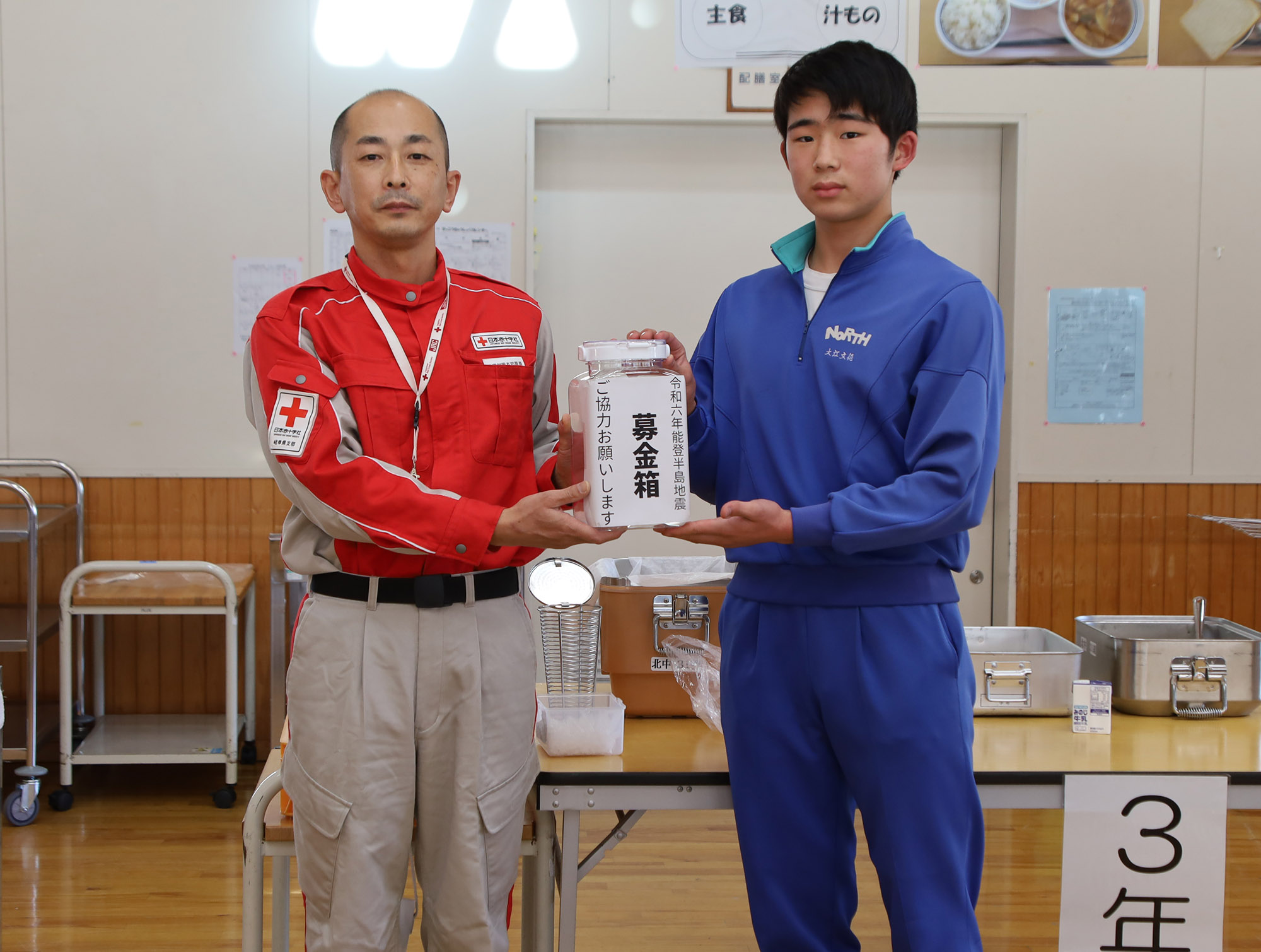 亀山さん（左）に義援金を手渡す恵那北中学校生徒会長の大江さん（右）