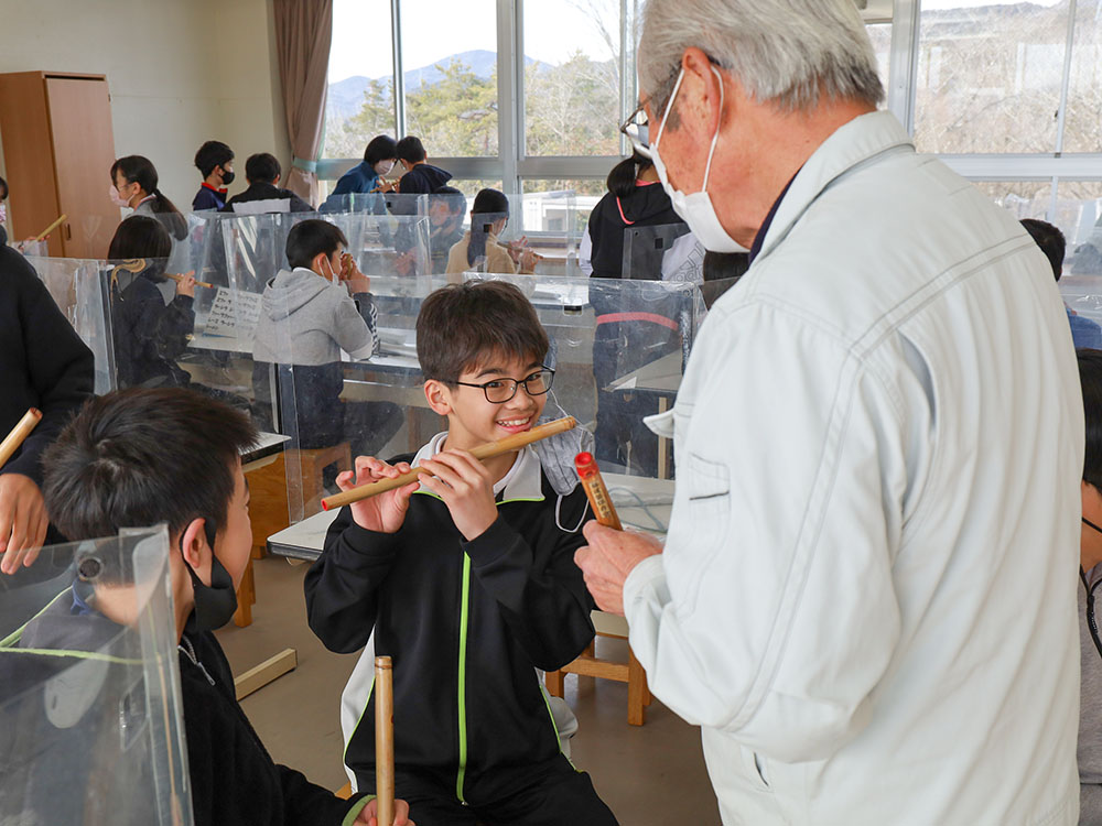 保存会の方から笛の演奏の指導を受ける児童