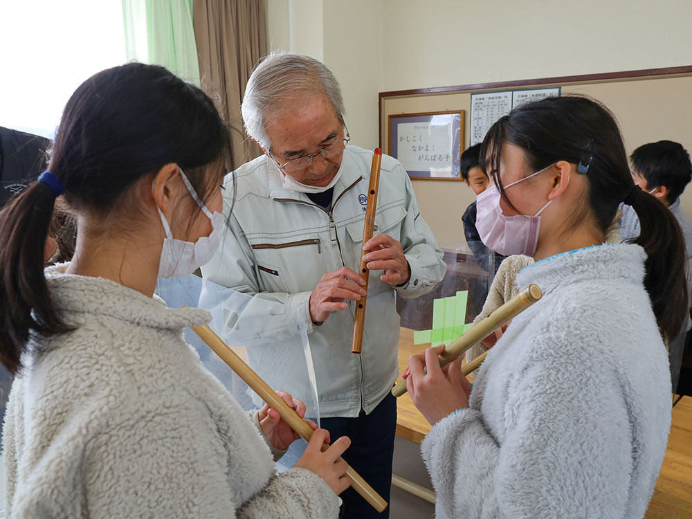 保存会の方から笛の演奏の指導を受ける児童