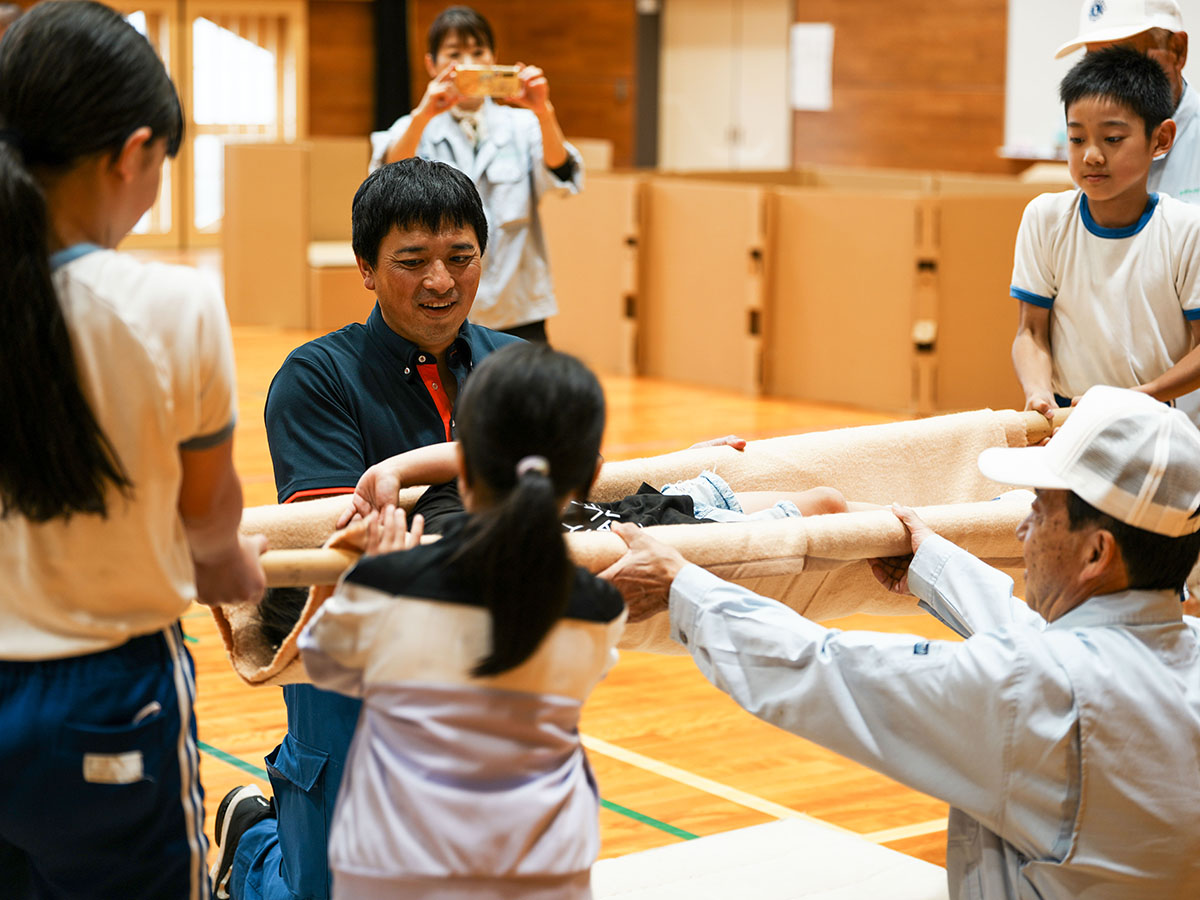 毛布を使った簡易担架を体験する児童ら