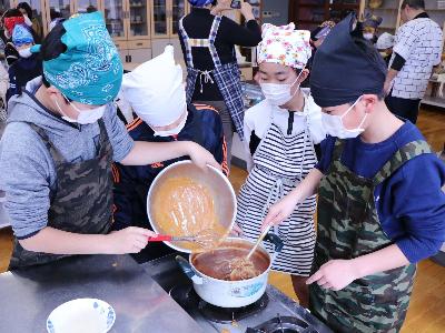炒めた小麦粉をルーに投入する児童