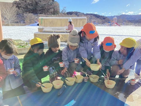 雪で氷あそびをする子ども