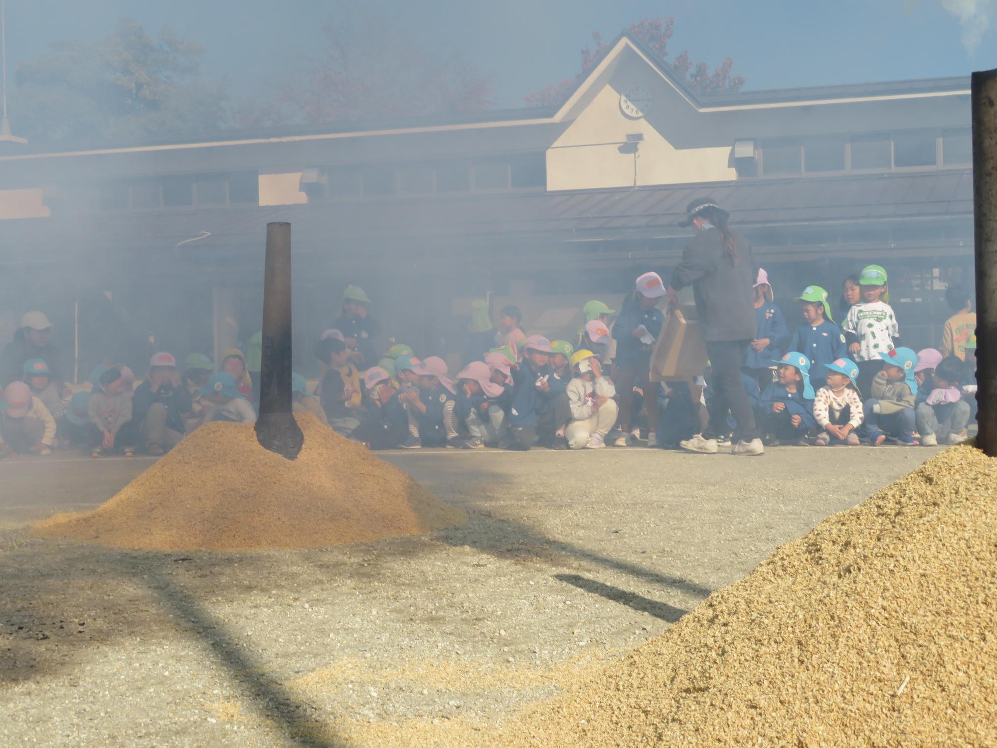 みんなでもみ合らの話を聞き、近くでもみ殻を観ています。