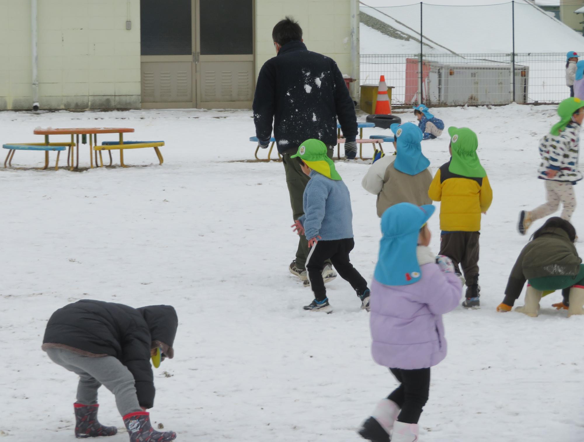 先生めがけて雪玉を投げる子ども達