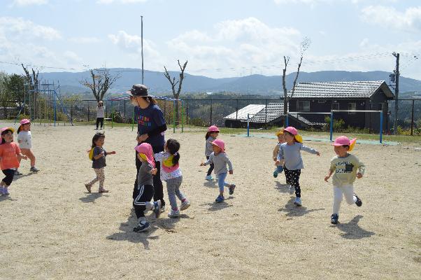 晴れた日に先生の周りを駆け回る子どもたち