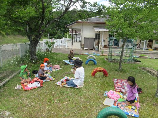 芝生の上で大人と子どもたちがピクニックをしている様子