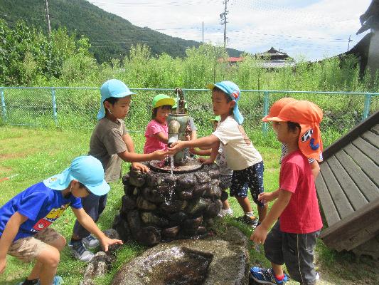 6人の子どもたちが井戸から水を汲み上げている画像