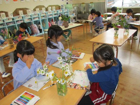 いくつかの机が並び、子どもたちが色塗りをしている様子