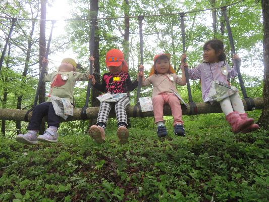 森の中の木で作られたブランコに乗る4人の子どもたち