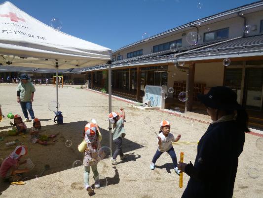よく晴れた日の園庭で子どもたちがシャボン玉遊びをしている様子
