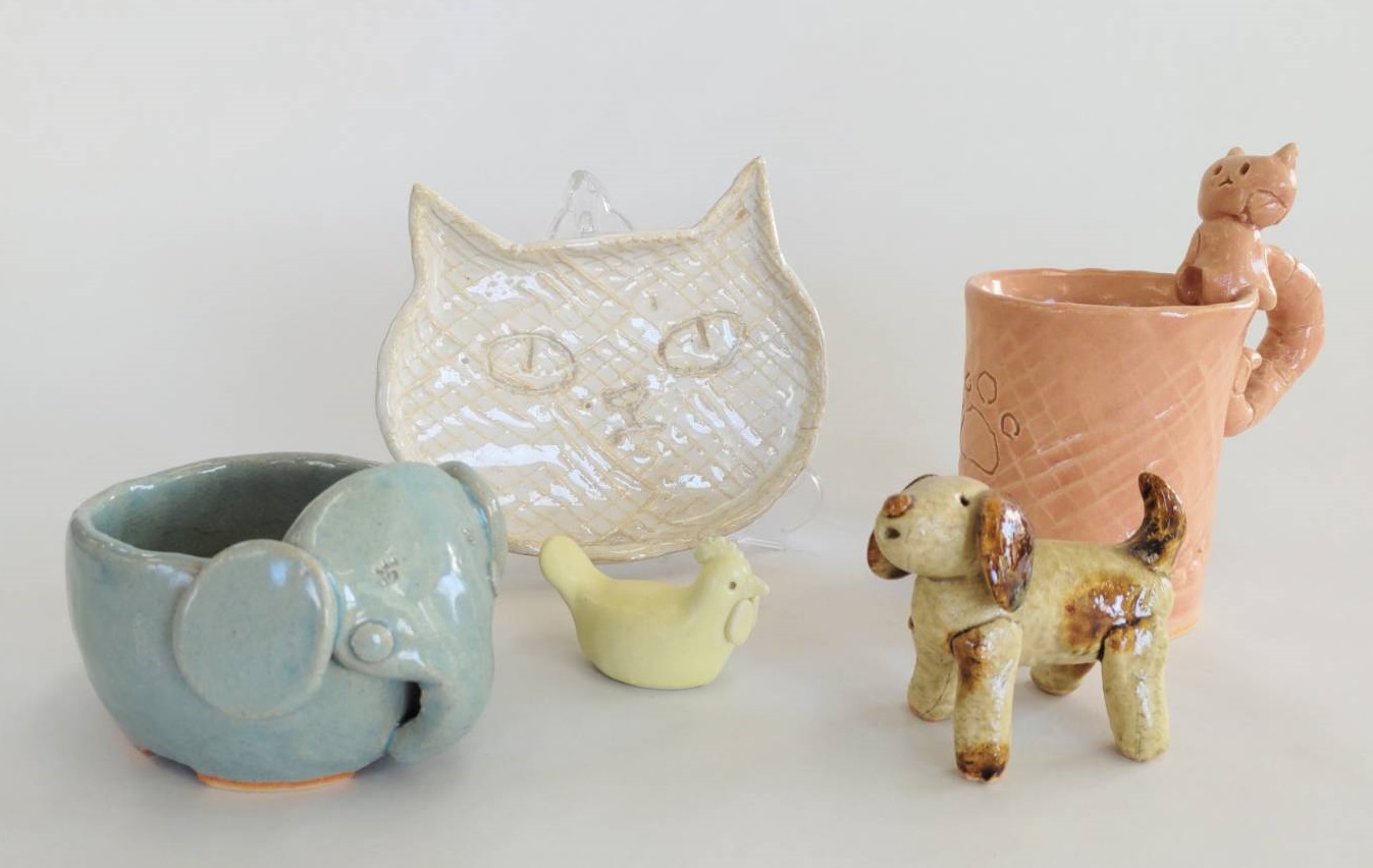 7月12日「ちびっこ夏休み」子どもたちの自由な発想で作る作品。水色の像やピンク色の取っ手に猫の付いたカップ、白色の猫のお皿や犬の置物の作品。