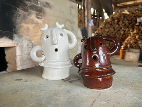 8月23日「はにわ」左手を頭に乗せ右手を腰に当てたお茶目な白色と茶色のはにわ。登り窯や薪の前で並んでポーズをとっている。